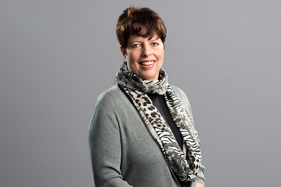 Femeia cu zâmbet poartă o eșarfă la modă în jurul gâtului.