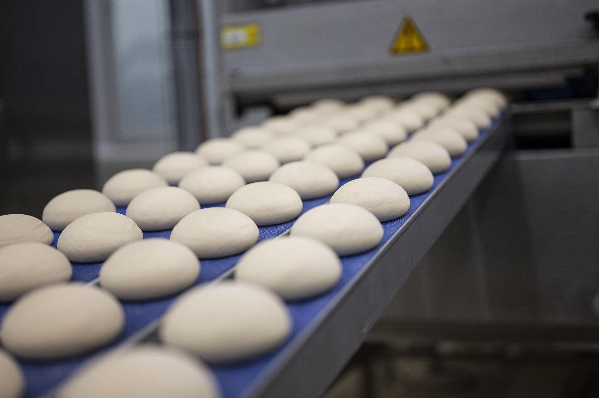 Obiecte albe rotunde pe o bandă transportoare într-o fabrică de produse alimentare.